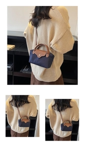 Detail of navy nylon crossbody bag with brown leather flap and golden metal button