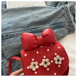 Détail du mini sac rouge à pois avec fleurs en feutre et un grand nœud en cuir élégant