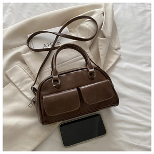 Detail shot of vintage dark brown Boston bag on white blazer with accessories