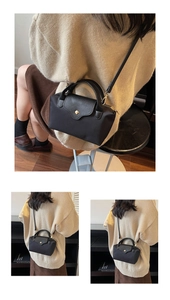 Detail of black nylon mini crossbody bag featuring leather flap and gold metal snap button