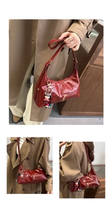 Detail view of red glossy patent leather shoulder bag with vintage half-moon design