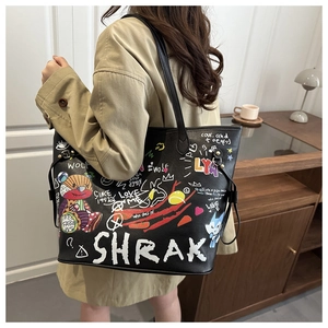 Detail view of black leather tote bag featuring colorful street graffiti and bear graphics