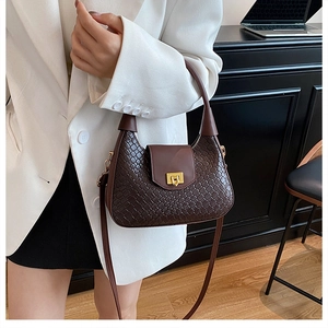 Détail d'un sac demi-lune en cuir tressé marron foncé avec fermoir doré rétro et bandoulière