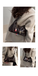 Detail of chocolate brown oiled leather tote bag with gold zipper and cute cow charm