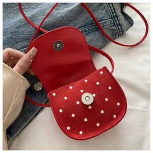 Détail d'un mini sac à bandoulière rouge à pois avec fermoir magnétique argenté
