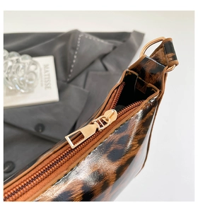 Close-up of golden zipper on glossy leopard print leather bag with fine texture