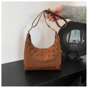 Detail of leopard print hobo bag featuring qaoihse logo and golden metal hardware