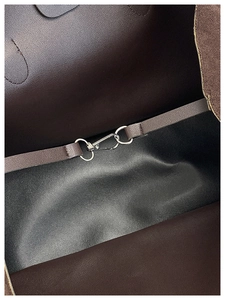 Detailed macro view of dark leather interior featuring a silver metal lobster clasp and strap