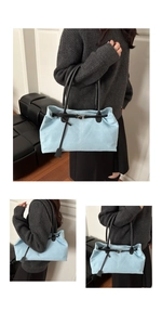 Detail of light blue canvas shoulder bag with black leather straps and tassel accent