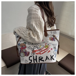 Detailed view of white graffiti tote bag with colorful cartoon prints and leather straps