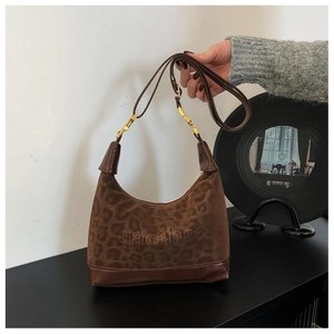 Detail of leopard print suede bag with gold hardware and embossed lettering logo