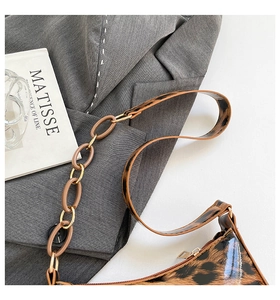 Close-up of leopard print shoulder bag with acrylic chain on grey blazer background