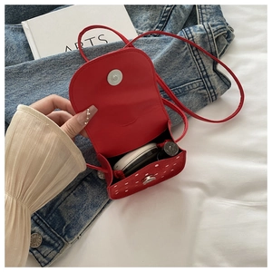 Détail du mini sac bandoulière rouge à pois montrant le fermoir magnétique et l'intérieur