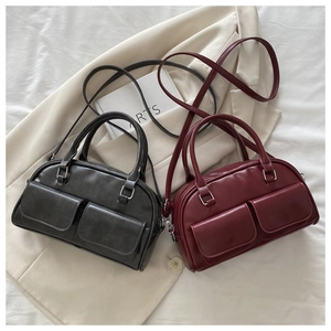 Detail of dual front pockets and metal buckles on a Boston style faux leather handbag
