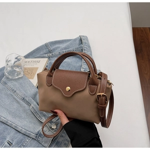 Detailed close-up of khaki mini bag with brown handles and white contrast stitching