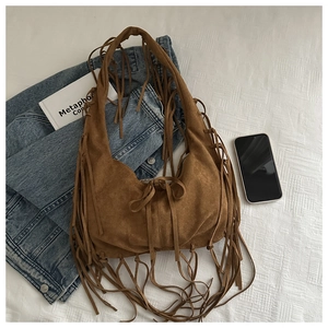 Détail d'un sac bandoulière en daim marron avec franges bohèmes et nœud de serrage