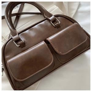 Close-up of dark brown vintage Boston bag featuring double front flap pockets and matte finish