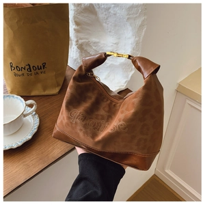 Detail view of brown leopard print handbag with gold hardware and leather base