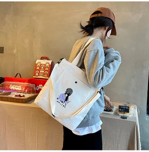 Detail of white canvas tote bag featuring purple cartoon girl print and Japanese text