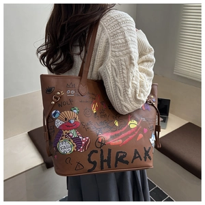Detail of a brown leather tote bag with colorful graffiti and bear print design
