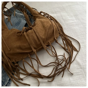 Détail du sac hobo à franges marron en daim avec un jean pour un style bohème