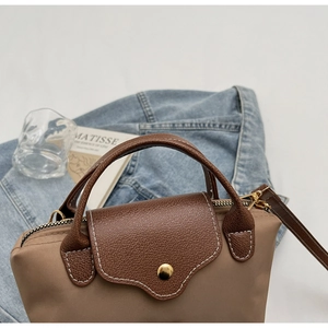 Close-up of contrast nylon bag with brown leather trim and golden snap button detail