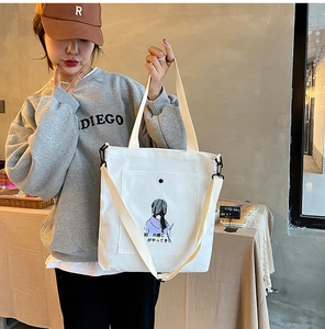 Close-up of white canvas tote bag featuring purple girl illustration and Japanese text