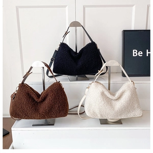 Borse a tracolla in peluche nero, caffè e beige esposte su un supporto minimalista