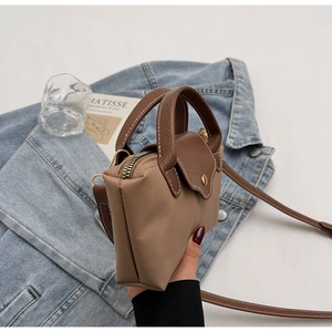 Close-up of khaki nylon handbag featuring brown lychee leather flap and gold zipper
