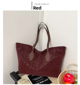 Detail view of red leopard print tote bag with brown leather straps on a black chair
