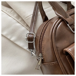 Detailed close-up of brown vintage Boston bag featuring silver metal zipper and hardware