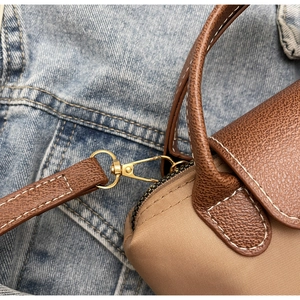 Detail of khaki nylon bag with brown leather handles and gold metal lobster clasp hook