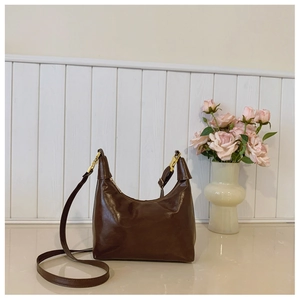 Brown vintage faux leather crescent bag with gold buckle on a clean white countertop