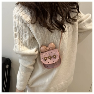 Détail d'un mini sac bandoulière rose à pois avec nœud et décorations florales en 3D
