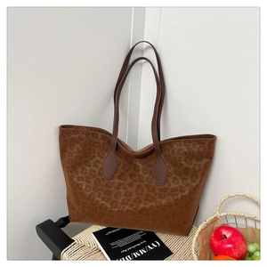 Detailed leopard print tote bag placed on a black chair with fruits and books