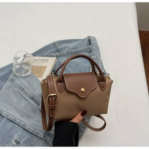Detail of khaki nylon handbag with brown leather flap and golden snap button detail