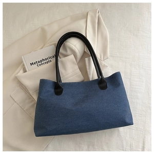 Detailed top view of a dark blue denim tote bag with black handles and white stitching