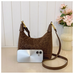 Detail of dark brown leopard embossed leather handbag with golden hardware and brand logo