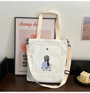 Detail of off-white canvas tote bag with girl illustration and adjustable shoulder strap