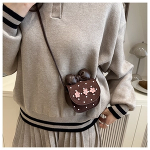 Gros plan d'un mini sac bandoulière marron avec fleurs roses et pois sur un mannequin
