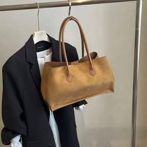 Retro brown suede underarm tote bag displayed on a hanger with a black suit jacket