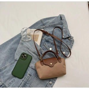 Detail view of contrast designer handbag with leather flap over a denim jacket