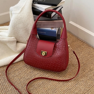 Sac hobo rouge foncé à motif crocodile avec fermoir doré sur un décor raffiné