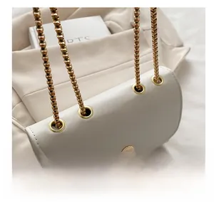 Detail der weißen Ledertasche mit goldener Kette durch metallische Ösen gezogen