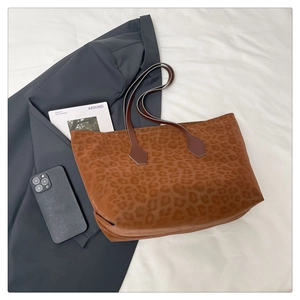 Macro view of a large leopard print tote bag with brown straps in a lifestyle setting