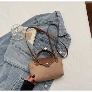 Detail of minimalist contrast shoulder bag with brown leather flap and gold metal snap button