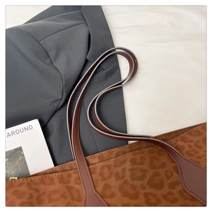 Detail of leopard print tote bag with brown leather handles and soft suede texture