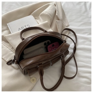 Detail shot of open deep brown Boston bag interior with smartphone and cosmetics