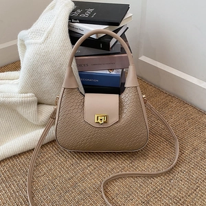 Sac à main tissé beige chic avec fermoir doré et bandoulière sur un fond de style cosy