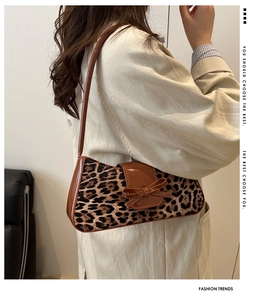 Close-up of leopard print shoulder bag with a leather bow and dark brown glossy strap